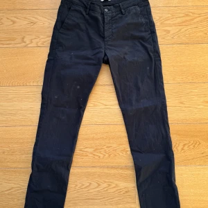Svarta byxor från NN07 - W31 - Säljer ett par svarta byxor från NN07 i modellen Joe. De är i bra skick och gjorda av 96% bomull och 4% elastan, vilket gör dem både bekväma och stretchiga. Perfekta för både vardag och fest! 🖤