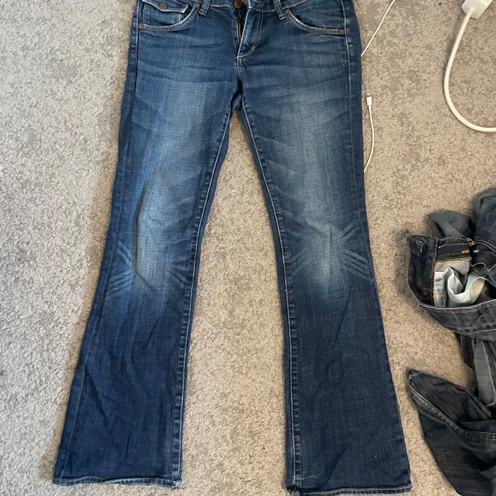 Säljer ett par snygga blå Lågmidjade bootcut jeans. De är lågmidjade och fickor  med knappar. Inga defekter! Skriv om du har mer frågor❤️storlek 28/32 inerbenslängd 75 midjemått 38. Jeans & Byxor.