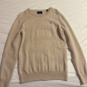 Beige premium  ulltröja från GANT - Säljer en superfin beige tröja från GANT i lammull. Den är i mycket bra skick och perfekt för höst och vinter. Tröjan har långa ärmar och en klassisk rund halsringning. Den är supermjuk och varm, perfekt för kalla dagar. Passar både till vardags och lite finare tillfällen. Tröjan är storlek s/xs. Original pris 1500kr