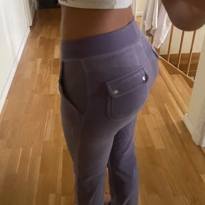 Lila Juicy Couture byxor - Dem är i bra skick förutom att den lilla silvriga grejen på snöret har lossnat. Just för att det saknas något vid snöret säljer jag dem för ett billigt pris, orginalpris är 1200. 