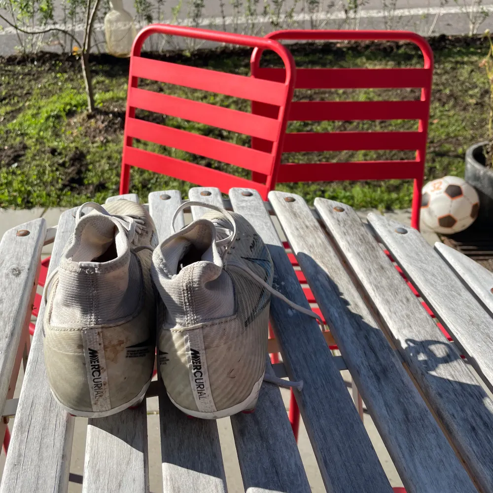 Säljer ett par Nike Mercurial fotbollsskor i en ljus färg med blå och röda detaljer. Skorna har snörning och är designade för att ge bra grepp på planen. De är i ett välanvänt skick men fortfarande funktionella för spel. Ny pris 1200. Skor.