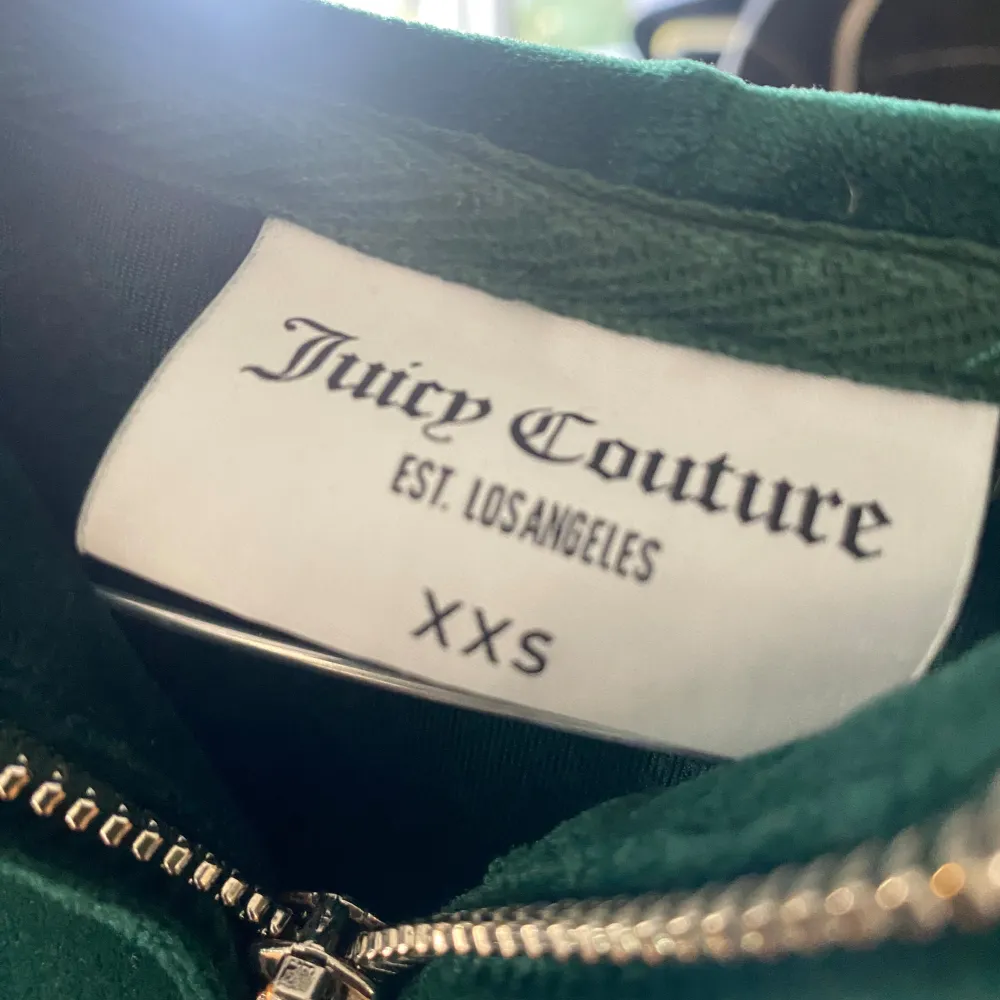 Säljer en superfin grön hoodie från Juicy Couture i storlek XXS. Den är gjord i mjuk velour och har en dragkedja framtill. På baksidan finns det glittriga 'Juicy'-text och på framsidan ett glittrigt emblem. Perfekt för en chill dag eller när du vill känna dig extra glam!. Tröjor & Koftor.