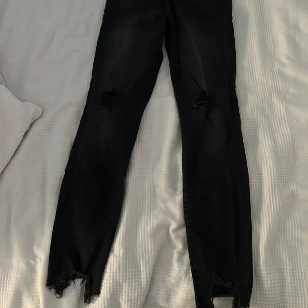 Säljer ett par svarta super skinny jeans med hög midja. De har en cool distressed look med slitna detaljer vid knäna och längst ned. . Jeans & Byxor.