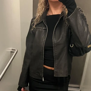 Faux skinnjacka, Gina Tricot  - Snygg skinnjacka med dragkedja framtill och en klassisk krage. Jackan har en tight passform och långa ärmar, perfekt för en stilren look. Den har även en diskret bröstficka med dragkedja💞