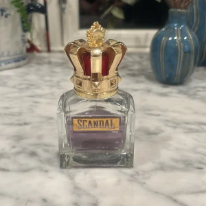 Scandal Parfym från Jean Paul Gaultier - Elegant parfymflaska med en kunglig krona som lock. Flaskan är genomskinlig med en lila vätska inuti och har en röd och stilig förpackning. Batchnummer finns på både flaskan och förpackningen, köpt för 800 spänn om jag ej minns fel och mitt pris är endast 450 kr. Den säljes då den inte riktigt faller mig i smaken, det finns ungefär 3/4 kvar är innehållet. Undrar du något så är det bara skicka ett pm! Köparen står för frakten.