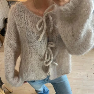 Mohair stickad kofta med knytning - Superfin beige stickad kofta med knyt framtill. Den är fluffig och perfekt för kyliga dagar. SUPER bra kvalitet med 80% mohair. Har ett litet hål, som man ser på tredje bilden. Inget man tänker på ALLS o man kan lätt sy ihop❤️❤️