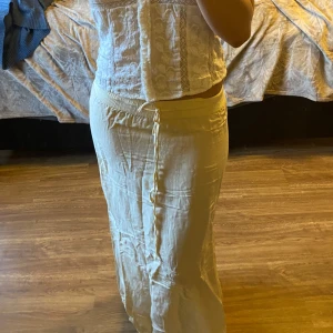 Beige långkjol med knytband linnekjol - Snygg beige långkjol med knytband i midjan. Kjolen har en avslappnad passform och en diskret slits framtill som ger extra rörelsefrihet. Perfekt för en somrig look!