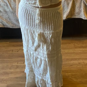 Vit långkjol med spetsdetaljer - Charmig vit långkjol med vackra spetsdetaljer och ribbad midja. Kjolen har en bohemisk känsla med knytband i midjan för justerbar passform. Perfekt för en somrig look. Den är totalt ca 88cm lång.🧸💓