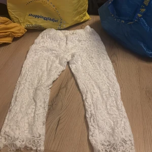 Vita spetsbyxor - Säljer ett par vita byxor i spets med vackra detaljer. Byxorna har en elegant design med spetsmönster och är perfekta för speciella tillfällen. De har en bekväm passform och är tillverkade i ett lätt material.
