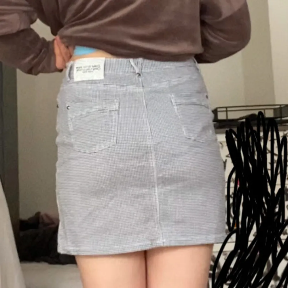Snygg rutig kjol från Zebra Style med klassiskt mönster i svart och vitt. Kjolen har en kort längd och små nitar i hörnen. . Hameet.