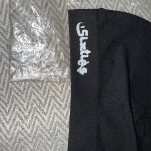 Svart mössa från Sixtie's - Snygg svart mössa från Sixtie's med logga i vitt. Perfekt för att hålla värmen under kyliga dagar. Enkel och stilren design som passar till det mesta.