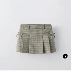 Rutig kortkjol med knytband - Trendig rutig kortkjol med knytband i sidorna. Kjolen har en klassisk plisserad design och är perfekt för en stilren look. Passar utmärkt till både vardag och speciella tillfällen. Kortare i modellen och är i storlek 164 skulle säga XS!
