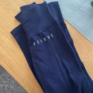 Mörkblå leggings från Relode - Snygga mörkblå leggings från Relode med hög midja och ribbade detaljer. Perfekta för träning eller en avslappnad dag. Materialet är stretchigt och bekvämt. Xs eller S. Knappt använda