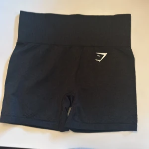 Svarta träningsshorts från Gymshark - Snygga svarta träningsshorts från Gymshark med hög midja och en tight passform. Perfekta för gymmet eller löprundan. Diskret logga på framsidan.