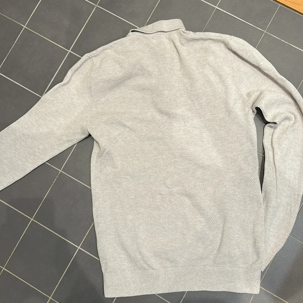 Snygg beige långärmad pikétröja från Bläck med krage och knappar framtill. Tröjan har en mycket snygg textur. Han på bilden är 183 cm 70 kg. nypris 699! ända defekt är ett pytte litet håll i armhålan . Neuletakit & Villapaidat.