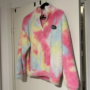 Färgglad fleece från Shein - Säljer en supermjuk och färgglad fleece från Shein i storlek S. Tröjan har en dragkedja framtill och ett märke på bröstet. Perfekt för att lysa upp din garderob med sina rosa, gula och blå toner.