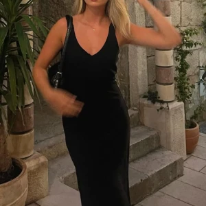 Svart ärmlös klänning - Elegant svart klänning med ärmlös design och v-ringad hals. Perfekt för en stilren look.