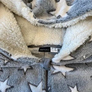 Grå OnePiece med stjärnor  - Supermysig grå OnePiece med vita stjärnor över hela. Den har en dragkedja framtill och en skön huva med fluffigt foder. Perfekt för kalla dagar 💫