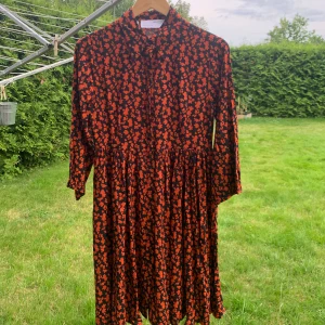 Blommig klänning från Selected Femme - Säljer en superfin blommig klänning från Selected Femme. Den har en mörk bas med ett härligt orange blommönster. Klänningen är långärmad och har en normal passform, perfekt för både vardag och fest.Selected Femme Slfleia 3/4 Short Shirt Dress.Helt nytt aldrig använd känns mjukt och skönt mot huden.