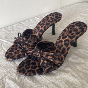 Leopard klackar  - Leopardklackar med öppen tå och rosettdetalj 