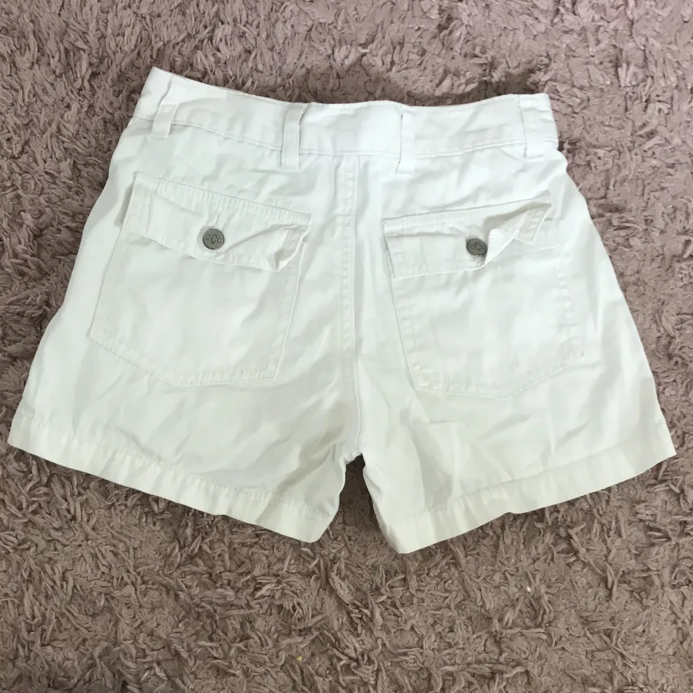 Säljer ett par vita shorts från C.C.C Girlswear. De har en normal passform med knappar fram och praktiska fickor både fram och bak. Perfekta för sommardagar!. Shorts.