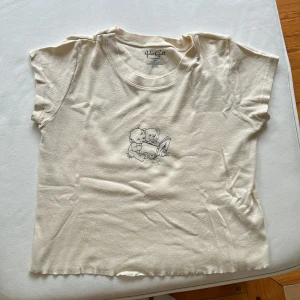 T-shirt med motiv - Beige t-shirt med en bebis och en nalle som motiv. Väldigt söt ☺️ 