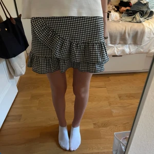 Svartvit rutig kjol från Pull&Bear - Säljer en superfin svartvit rutig kjol från Pull&Bear. Den har en söt volangdetalj längst ner som gör väldigt mycket☺️