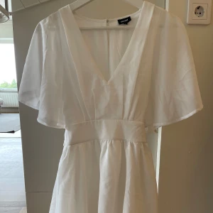 Vit klänning från Bubbleroom - Säljer en superfin vit klänning från Bubbleroom i storlek 34. Den har en v-ringad design och korta ärmar som ger en luftig känsla.  Enbart testad, men tog bort lappen. Perfekt för sommarens alla fester! 🌸