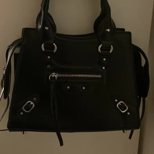 Svart väska med nitar - oanvänd svart väska med silver nitar och lite fransar. Finns ett längre band till 