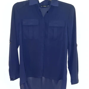 Mörkblå blus med fickdetaljer - Snygg mörkblå blus med långa ärmar och stilrena fickdetaljer på bröstet. Perfekt för en utekväll med vänner. Blusen har en klassisk krage och knappar framtill. (Inte så blå som den ser ut på första bilden) kan betalas med Swish 