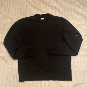 Svart tröja från C.P. Company - Säljer en svart CP Company sweatshirt i riktigt bra skick. Enkel och snygg design som passar både till vardags och lite mer avslappnade tillfällen. Skön att ha på sig och gjord i bra kvalitet. Perfekt för dig som gillar stilrena plagg som håller länge! Nypris: 2000 Mitt pris: 400