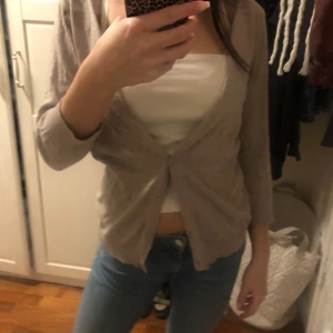 Beige kofta - Säljer en beige kofta med trekvartsärmar och knappar framtill. Perfekt för lager-på-lager och passar till många olika outfits. Koftan är i ett mjukt material och har ribbade muddar vid ärmslut och nederkant💗💗Storlek M men är nog mer som en S🫶🏻