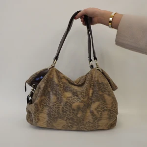 Beige axelväska med ormmönster - Snygg beige axelväska med ormmönster och mörka handtag. Väskan har en rymlig design och är perfekt för att bära med sig alla nödvändigheter. Den har metallringar som fäster handtagen och ger en stilren look.💜