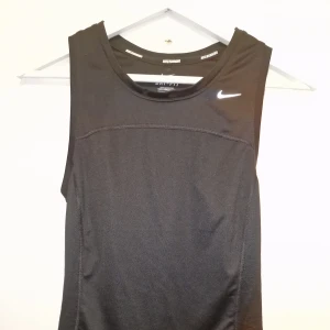 Svart träningslinne från Nike - Säljer ett svart träningslinne från Nike med Dri-FIT-teknologi. Den är tillverkat i ett lätt och andningsbart material. Kommer inte till användning därav säljes det. Garderobsrensning så kika gärna på övriga auktioner.