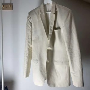 Beige kavaj - Snygg beige kavaj med två knappar framtill och fickor. Perfekt för en stilren look. Passar bra till både formella och semi-formella tillfällen.