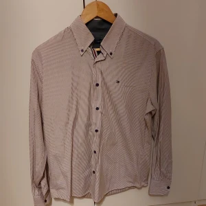 Randig skjorta från Tommy Hilfiger - Snygg randig skjorta från Tommy Hilfiger i en klassisk design. Skjortan har långa ärmar och knappar framtill. Perfekt för en stilren look.