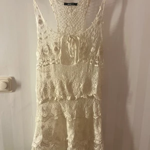 Vit spetsklänning från Gina Tricot - Säljer en vacker vit spetsklänning från Gina Tricot. Klänningen är ärmlös med ett fint knytband i ryggen och har ett detaljerat spetsmönster. Perfekt för sommarens alla tillfällen. 🌸