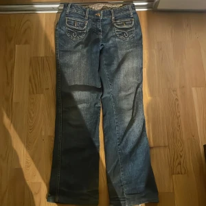 flared jeans med fickor - flared jeans med snygga fickor där bak. orange guldiga knappar och design på fickorna. skriv om fler frågor!