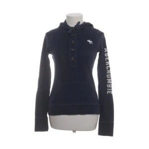 Abercrombie hoodie - snygg mörkblå hoodie från Abercrombie med knappar framtill och en vit logga på ärmen. 