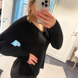 Svart stickad tröja - Säljer en svart stickad tröja med v-ringad hals. Tröjan har långa ärmar och en bekväm passform. Perfekt för kyligare dagar. Det är en xs men sitter som en s!!🥰