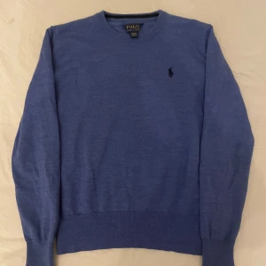 Blå tröja från Polo Ralph Lauren - Säljer en stilren blå tröja från Polo Ralph Lauren.  Tröjan Har 3 små hål i sig. Om ni har några frågor om tröjan kan ni bara att fråga.