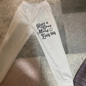 Vita mjukisbyxor med tryck - Vita mjukisbyxor med elastisk midja och texten 'Have a Good Mood Every day' tryckt på benet. Perfekta för en avslappnad stil.