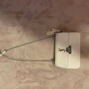 Ysl väska  - Snygg vit axelväska med silverkedja och dekorativ tofs. Man kan ha den som krosbody och Axel väska, knappt andvänd 