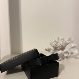 Svart armband i metall - Stilrent svart H armband i metall med en modern och minimalistisk design. Perfekt för att ge en elegant touch till din outfit. Armbandet har en enkel låsmekanism som gör det lätt att ta på och av. Köpt för 1200 och aldrig använt.