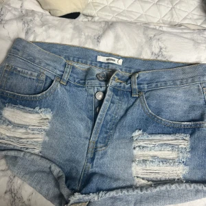 Blå jeansshorts från bikbok - Snygga blå jeansshorts från bikbok med slitna detaljer och  tre knappar. 