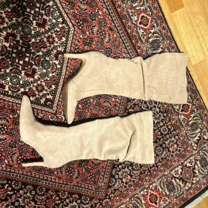 Beige stövlar med spetsig tå - Snygga beige stövlar med spetsig tå och hög klack. Perfekta för att ge en elegant touch till din outfit. De har en stilren design och är gjorda i ett mjukt material.