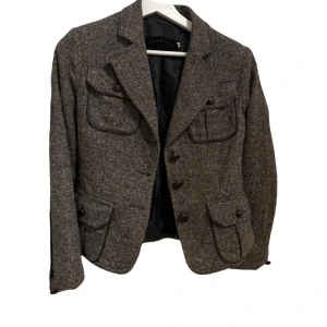 Brun kavaj från Imperial - Snygg brun kavaj från Imperial med klassisk design. Den har knappar framtill och flera fickor med lock. Tillverkad i Italien med ett stilrent mönster. Perfekt för en elegant look. Står M men är mer av en stil S. Utmärkt skick. 