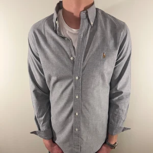 Grå Ralph lauren skjorta - Nu säljer vi ännu en fet polo skjorta som passar till alla tillställningar, skjortan är i mycket bra skick. Du ska kunna utrycka stil utan att det kostar för mycket !🕺🍾💼🤩  Storlek👔: M Nypris💰: 1499kr 