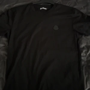 Svart t-shirt från Moncler - Snygg svart t-shirt från Moncler med en diskret logga på bröstet, Som ny 