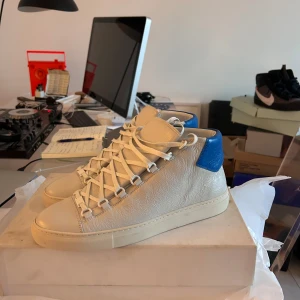 Skicka bud  - Snygga vita sneakers från Balenciaga med blå detaljer på hälen. Skorna har en stilren design med snörning och är tillverkade i skinn. Perfekta för en trendig look. SZ 44 sitter som 45-46 Helt nya. 